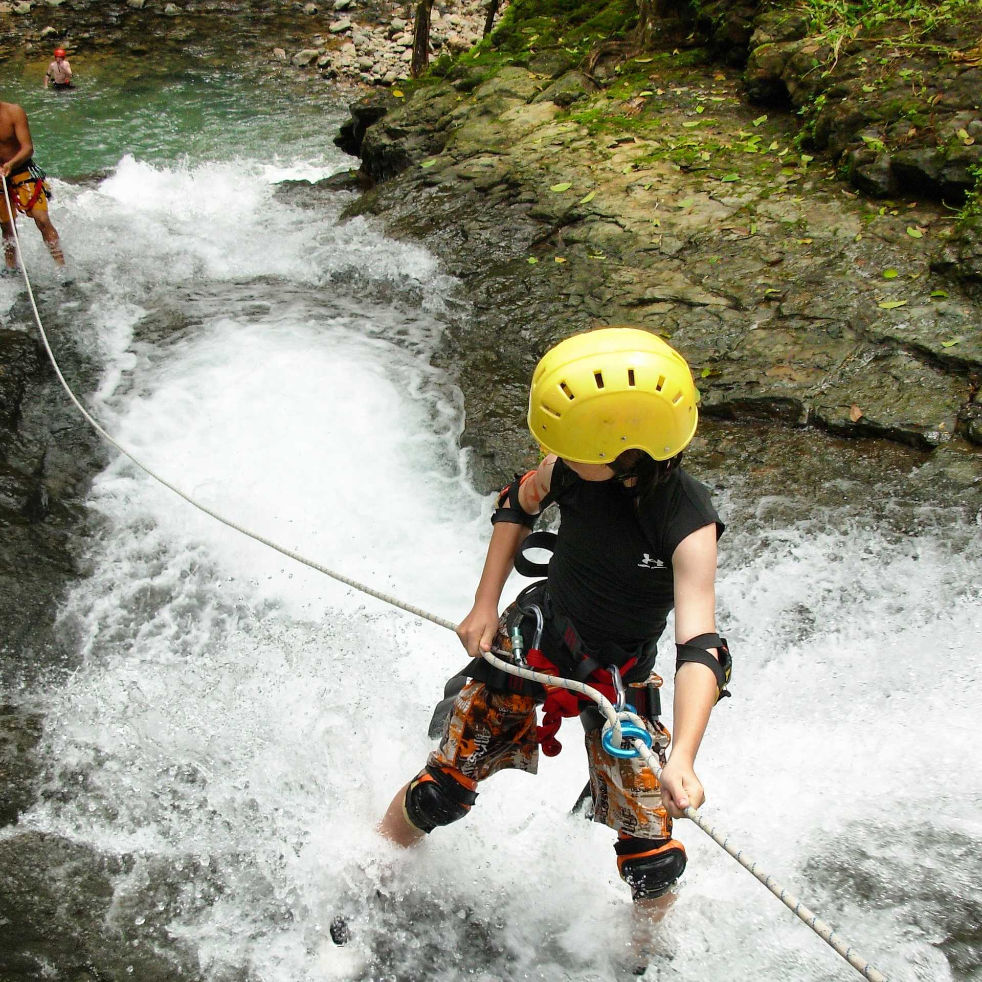 A child doing rappel down a river