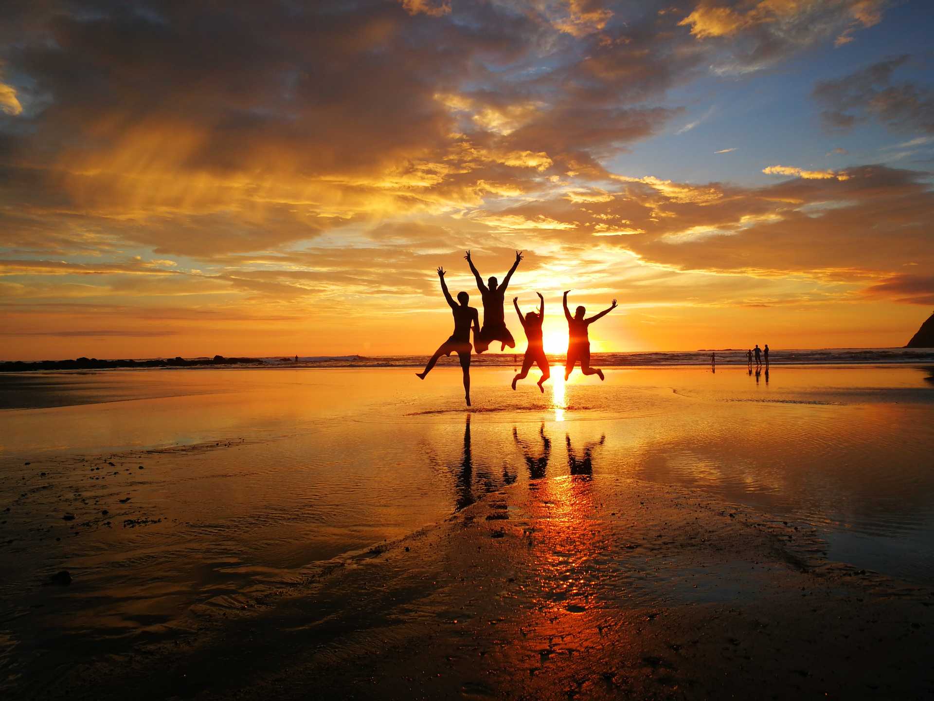 A group of people having fun at the beach at sunset